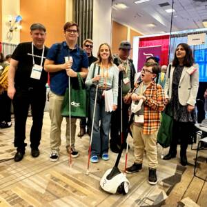 The Glidance team and others standing together. Many hold white canes and a youth holds the new Glide product.