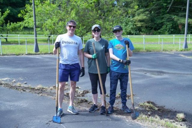 deloitte-4 A Deloitte volunteer, a HKS female staff member, and a male participant smiling while holding gardening tools. All three of them are wearing gardening gloves and black sunglasses.