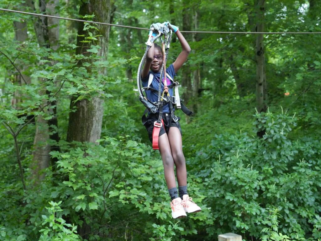 A female camper from Camp Helen Keller rides on a zipline. 