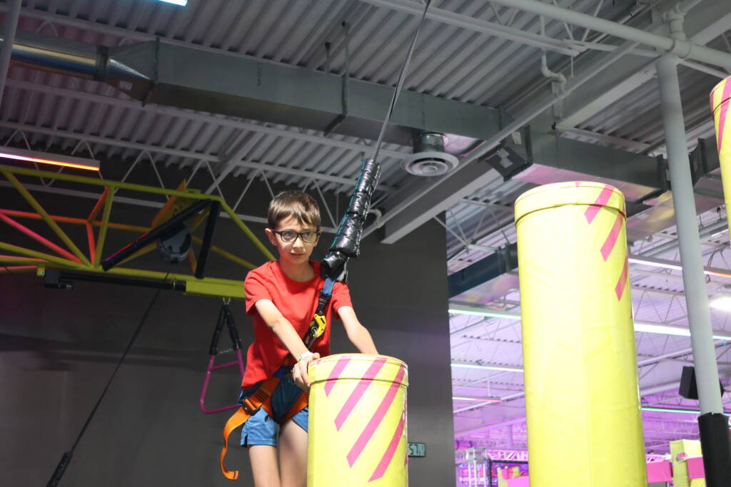 A boy camper climbs on an obstacle course,