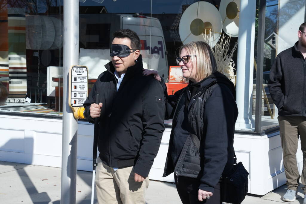 An HKs staff member guides a traffic engineer under blindfold through a cross walk. 
