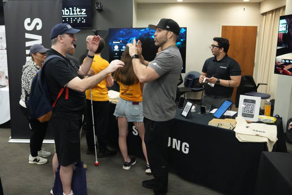 An attendee and interpreter communicate in ASL in front of the Samsung table.