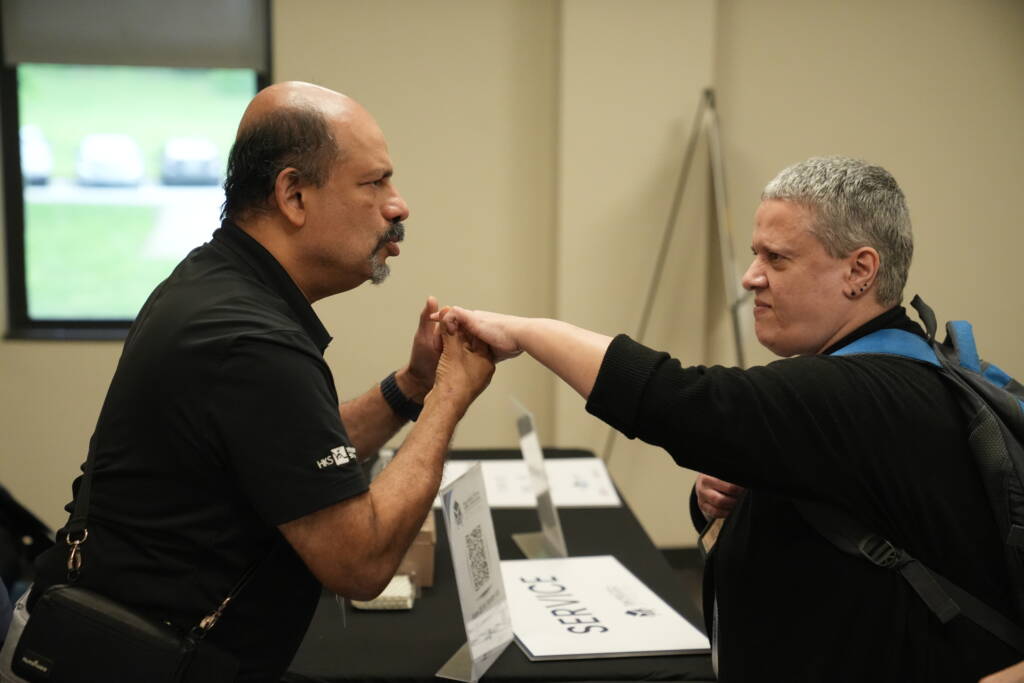 Bapin communicating in tactile ASL with an attendee.