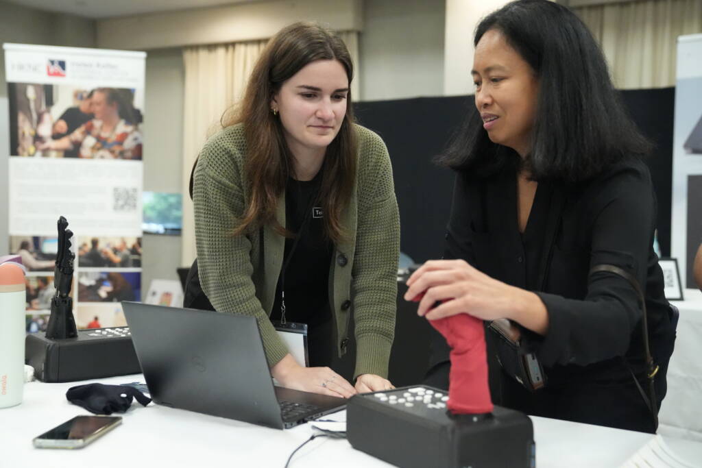 Maricar engages with the Tatum Robotics T1 fingerspelling hand, while Samantha Johnson looks on.