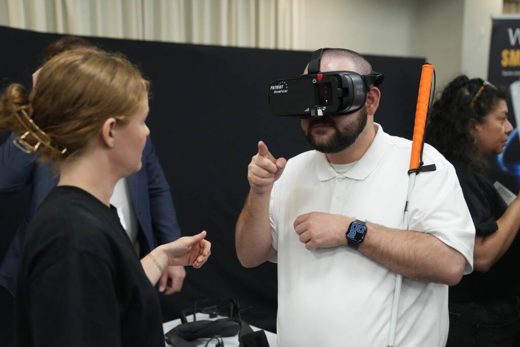 An HKNC participant attending Tech Blitz tries on The Patriot ViewPoint wearable low vision device.