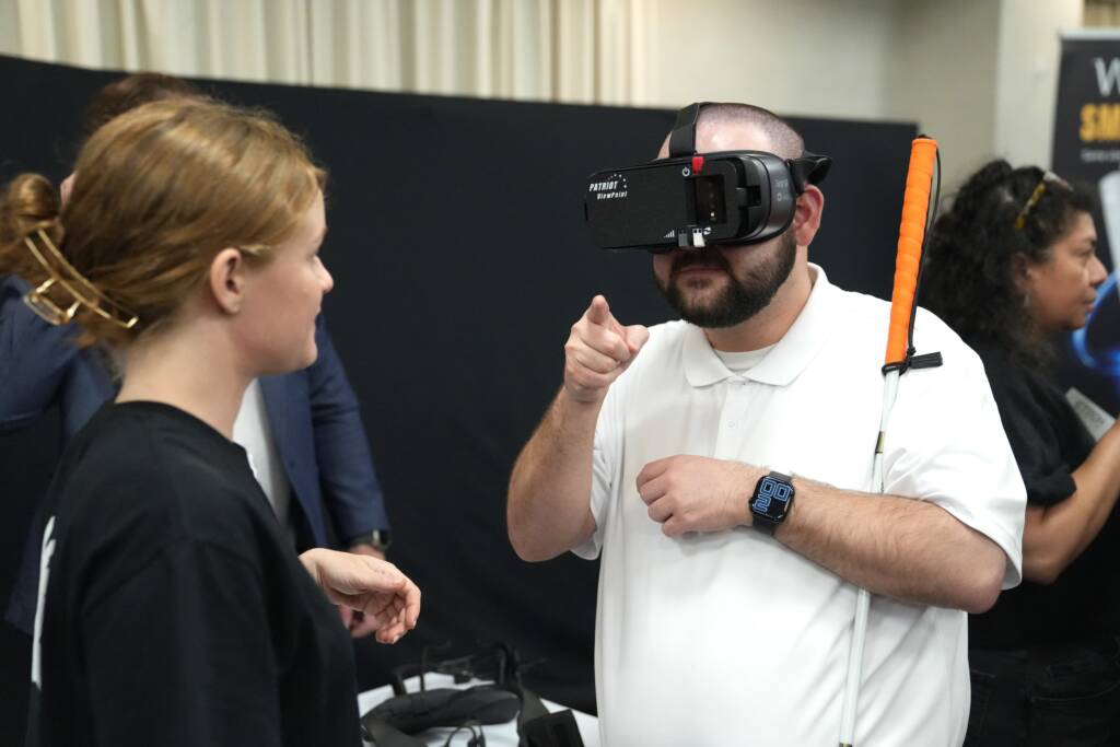 An HKNC participant and Tech Blitz attendee tries on The Patriot ViewPoint wearable low vision device.