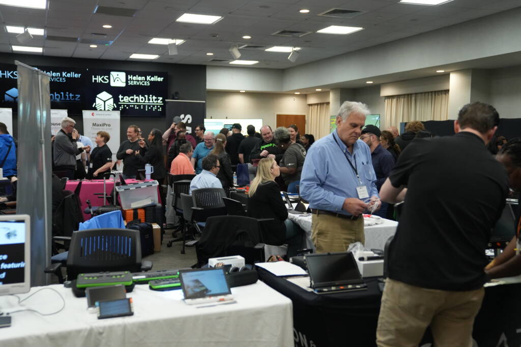 A conference center filled with attendees and assistive technology vendors.