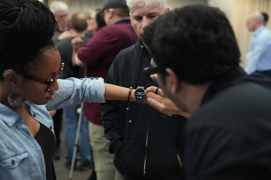 An attendee tries out Samsung's smart watch accessibility features with the help of vendor staff.