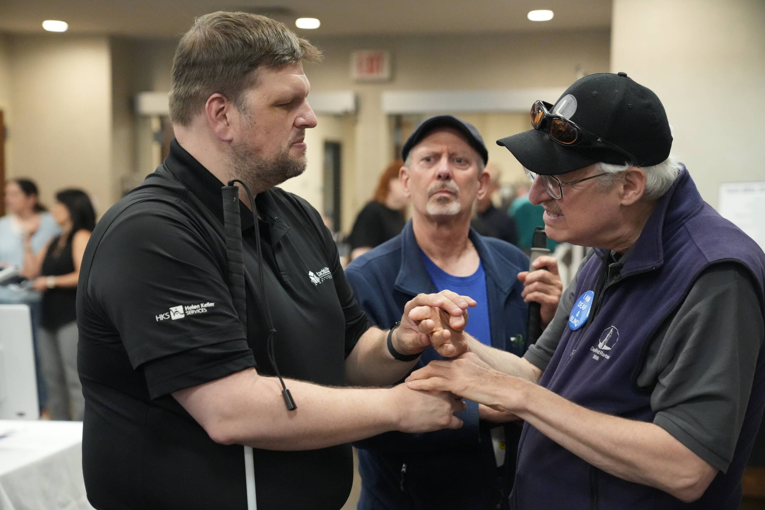 Ryan Odland communicates with a an older adult who is DeafBlind in tactile ASL.