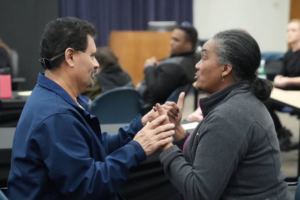 An HKNC Participant and staff member communicate in tactile ASL.