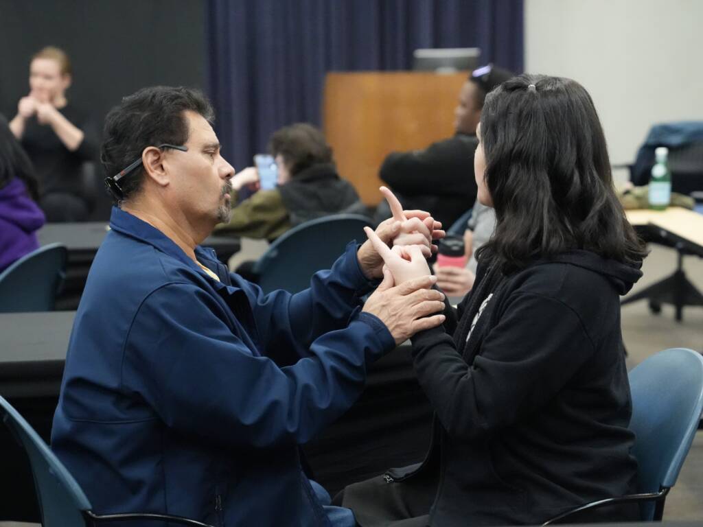 A DeafBlind individual communicates in tactile ASL with an interpreter. 