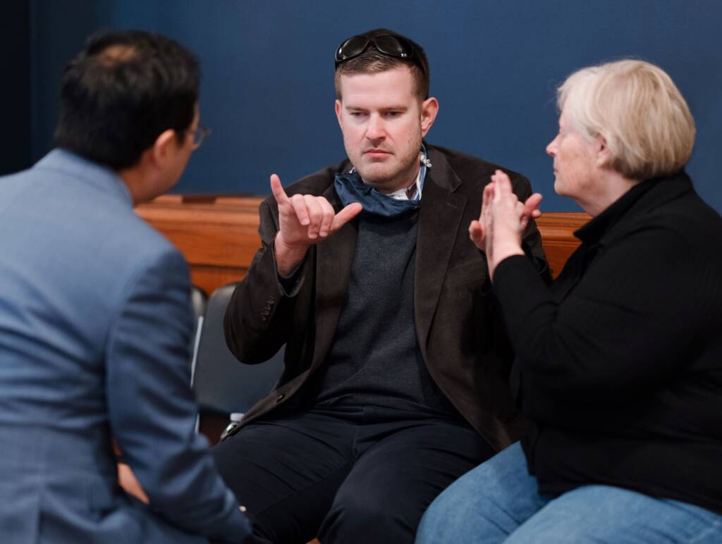 Jon Gabry signing with one hand while receiving tactile ASL communication with the other.