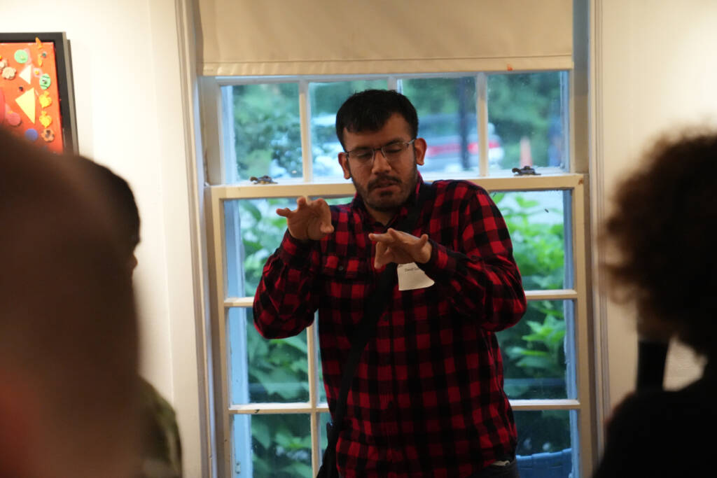 An HKNC participant engages with attendees, communicating in ASL while an interpreter off camera voices what he is saying. 