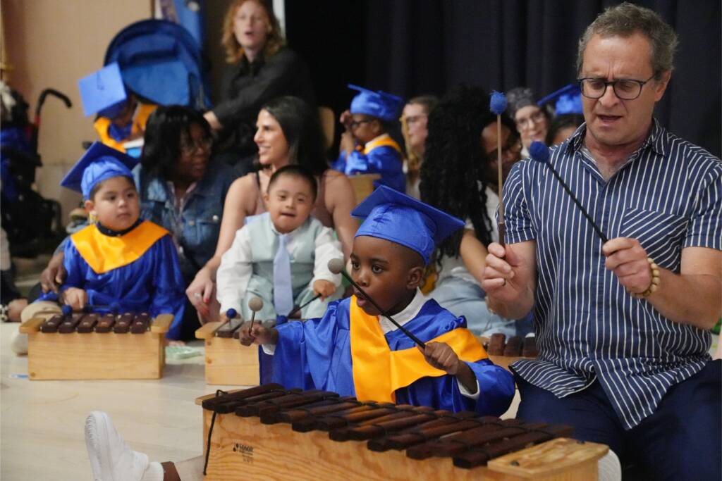 Preschoolers and staff on stage during a musical performance.