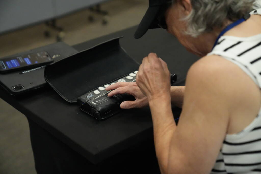 An older adult uses a braille display.