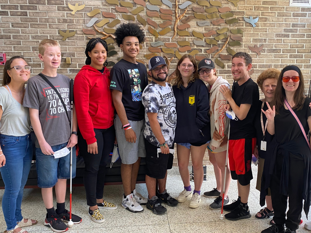A group of youth program participants and one adult standing in HKNC lobby.