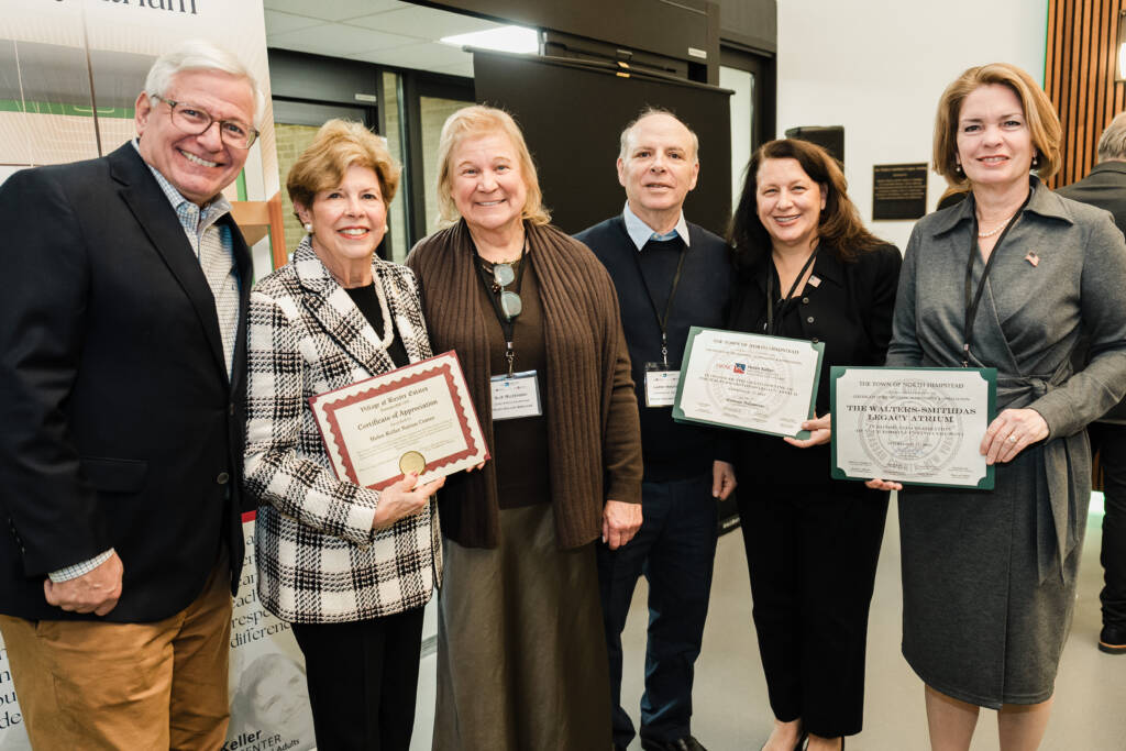 Six people stand together holding ceremonial certificates and proclamations.