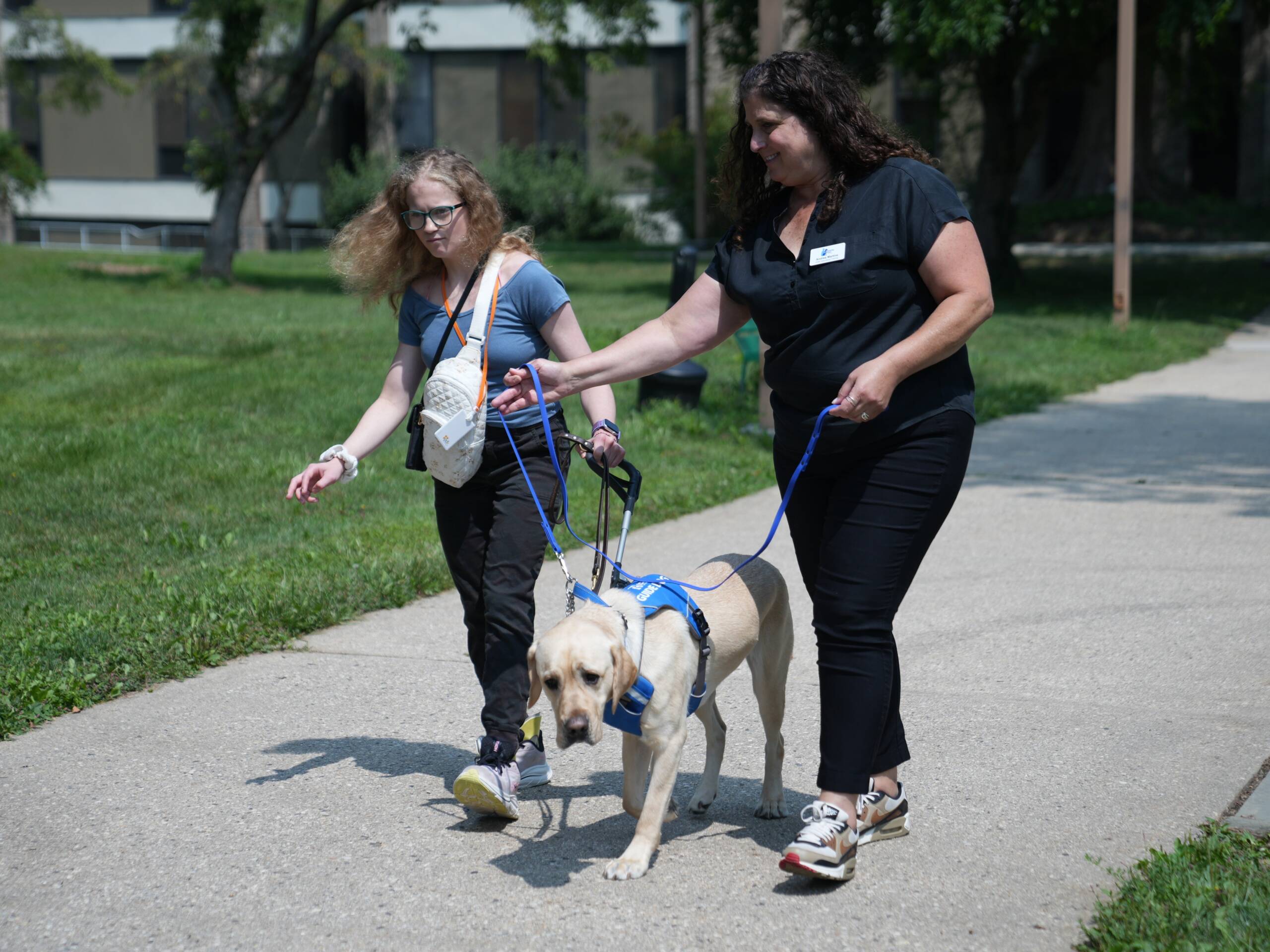 A female HKNC participant is guided on a Juno walk with a guide dog and trainer.