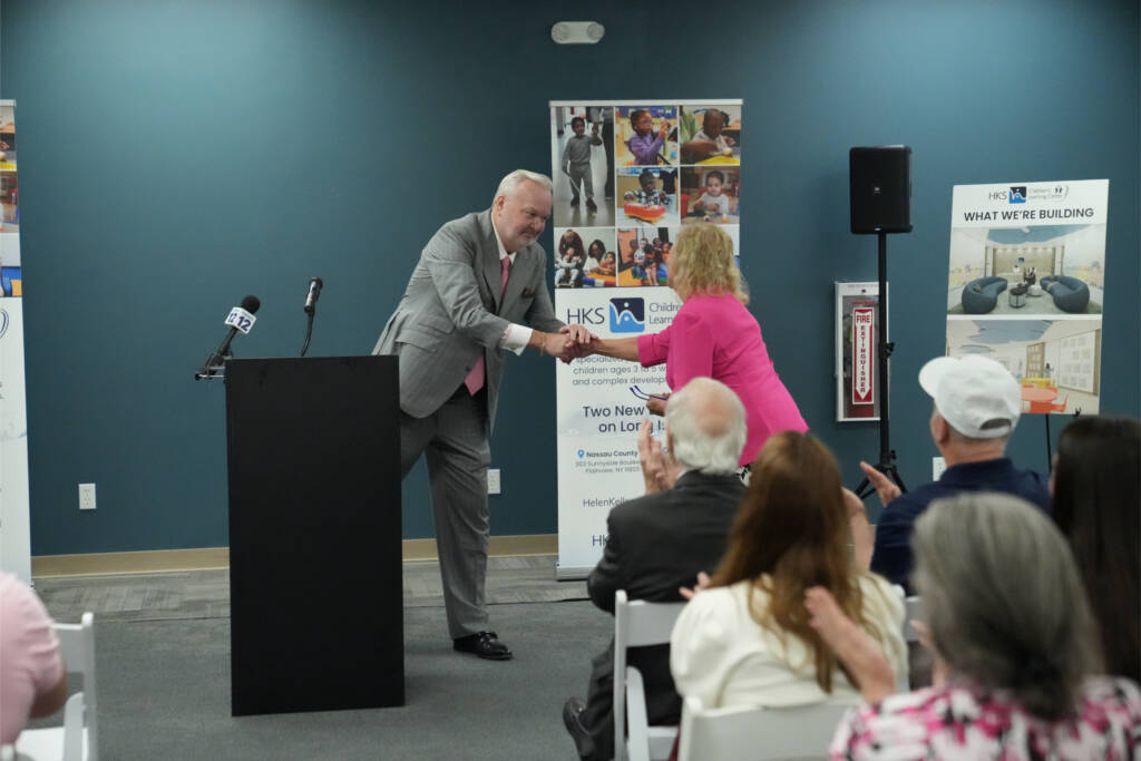 Rory Whelan shakes Dr. Susan Ruzenski's hand at the podium after speaking on behalf of Suffolk County Executive Ed Romaine.